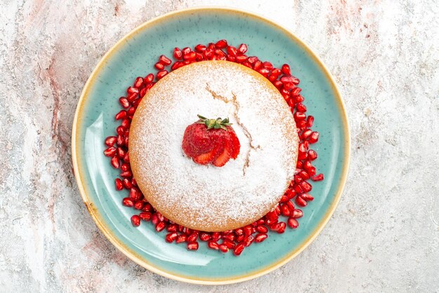 Vista ravvicinata dall'alto torta appetitosa torta appetitosa con fragole e semi di melograni sul piatto blu