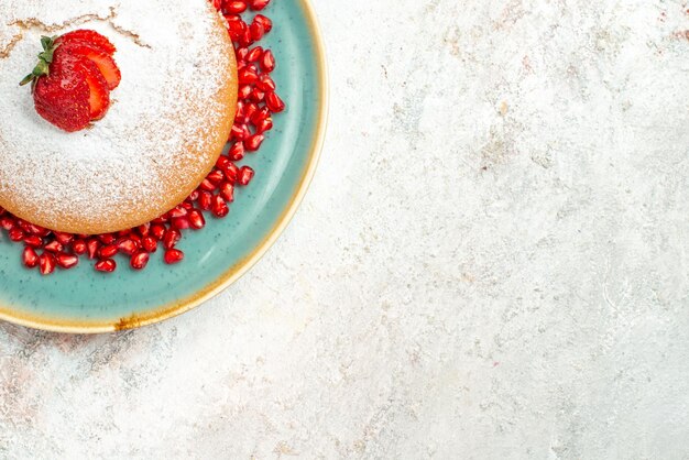 Vista ravvicinata dall'alto torta di fragole piatto di torta con fragole e melograno sul tavolo luminoso