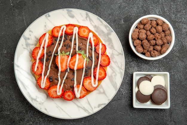 Vista ravvicinata dall'alto torta e dolci ciotole di nocciole e cioccolato e torta con cioccolato e fragole