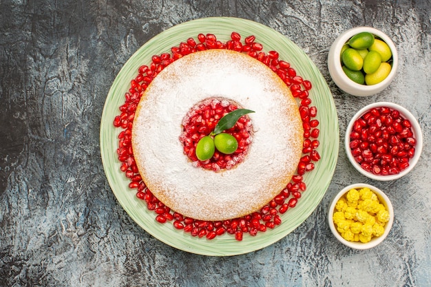 Vista ravvicinata dall'alto torta e dolci un piatto di torta con ciotole di melograno di caramelle agli agrumi