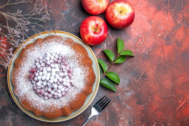 Vista ravvicinata dall'alto torta una torta con frutti di bosco forchetta mele foglie rami