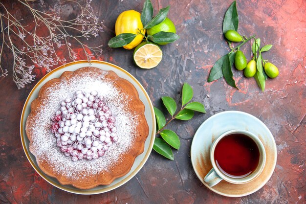 Vista ravvicinata dall'alto torta una torta con zucchero potenziato agrumi con foglie una tazza di tè