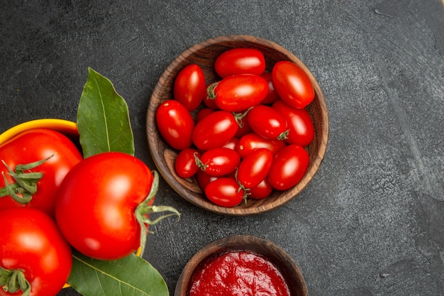 Vista ravvicinata dall'alto un secchio con ciotole di pomodori con pomodorini e ketchup su fondo scuro con spazio libero