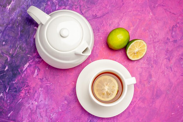 Vista ravvicinata dall'alto una tazza di tè teiera bianca una tazza di tè nero e lime sul tavolo rosa