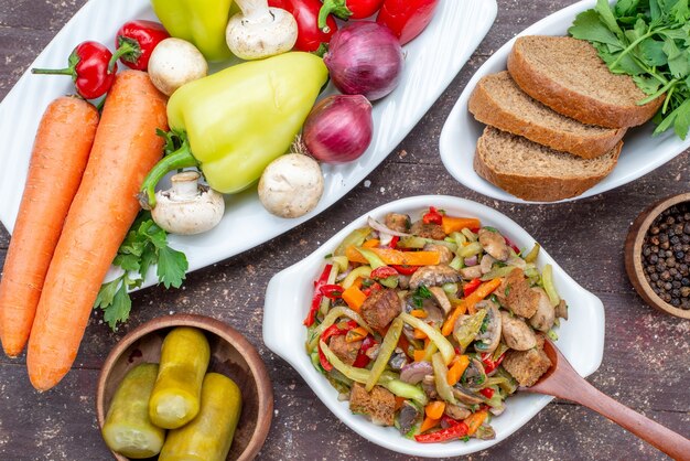 Vista ravvicinata deliziosa insalata di carne con carne affettata e verdure cotte insieme a verdure di pane sottaceti su carne marrone, piatto di farina di cibo