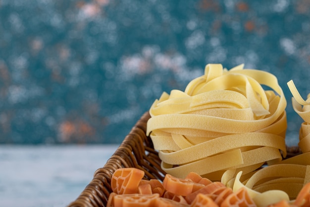 Vista ravvicinata dell'assortimento di pasta cruda nel cesto di legno.