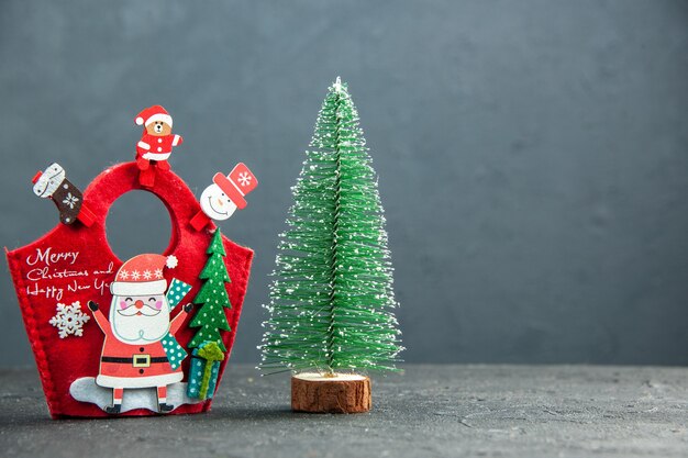 Vista ravvicinata dell'atmosfera natalizia con accessori decorativi sulla confezione regalo di Capodanno e albero di Natale sul lato destro su superficie scura