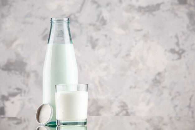 Vista ravvicinata della bottiglia di vetro e della tazza riempita con tappo per il latte su sfondo di colori pastello con spazio libero