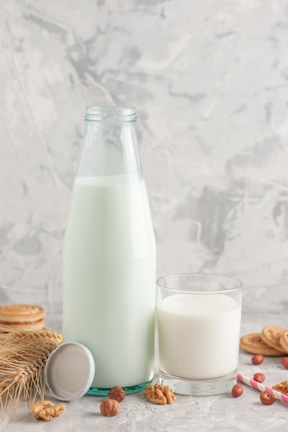 Vista ravvicinata della bottiglia di vetro riempita con tappo di latte e biscotti con punte di arachidi caramelle alle noci sulla superficie bianca macchiata