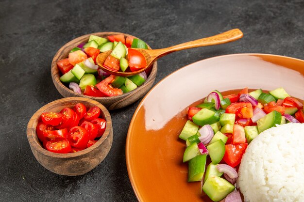 Vista ravvicinata della cena vegana con riso e diversi tipi di verdure sul tavolo scuro