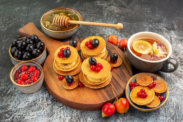 Vista ravvicinata della colazione con frittelle di frutta e tè servito con miele e ciliegie