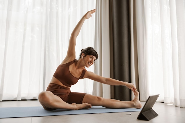 Vista ravvicinata della donna sorridente che fa esercizio di stretching sul laptop