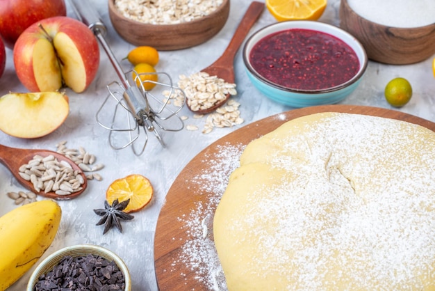 Vista ravvicinata della farina di pasticceria cruda sulla grattugia a bordo rotondo frutta fresca marmellata biscotti cioccolatini su sfondo bianco macchiato