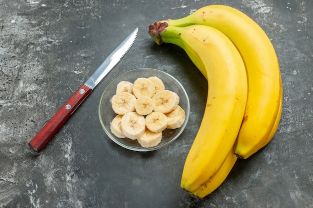 Vista ravvicinata della fonte nutrizionale di banane fresche fascio e tritato in un vaso di vetro su sfondo grigio