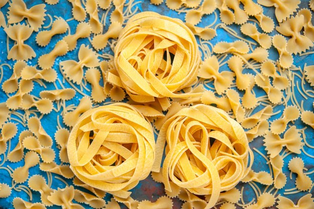 Vista ravvicinata della preparazione della cena con spaghetti di pasta allineati in fila su sfondo blu