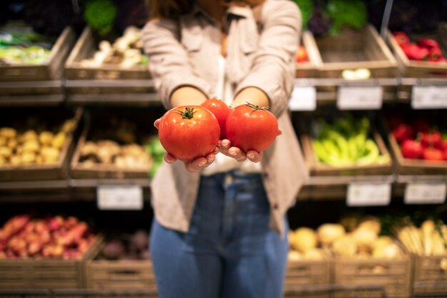Vista ravvicinata delle mani che tengono i pomodori verdure nel supermercato