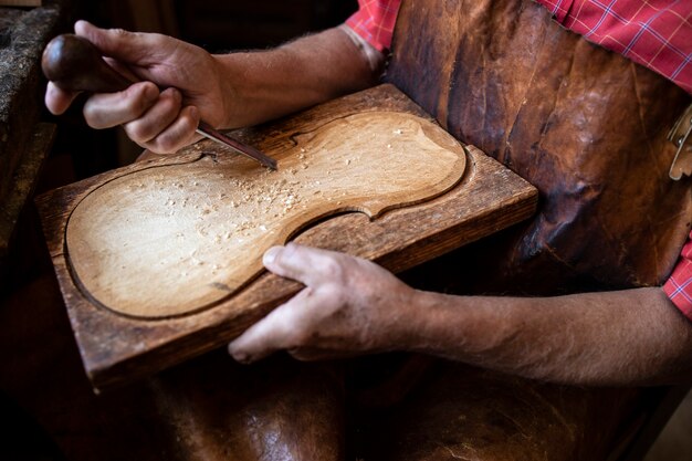 Vista ravvicinata delle mani del falegname che modellano e intagliano il legno nel suo vecchio laboratorio di moda