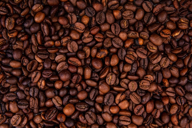 Vista ravvicinata di chicchi di caffè tostati freschi scuri su sfondo di chicchi di caffè