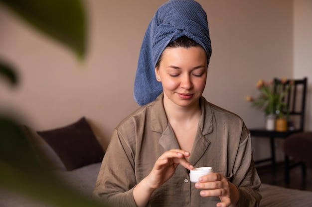 Vista ravvicinata di donna affascinante con crema sul viso a casa