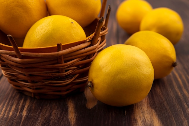 Vista ravvicinata di limone assaggiato acido su un secchio con limoni isolato su una parete in legno