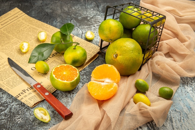 Vista ravvicinata di limoni freschi in un cesto nero caduto su un coltello per asciugamani e un giornale su un tavolo grigio