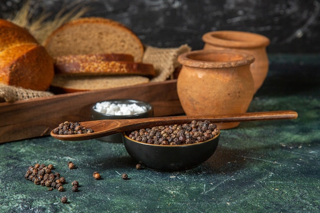 Vista ravvicinata di tutto e tagliare il pane nero fresco sul tovagliolo in una scatola di legno marrone potteries spezie sulla miscela scura colori superficie