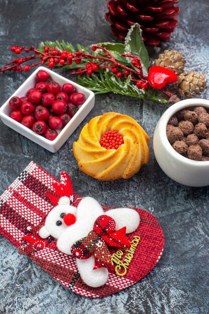 Vista ravvicinata di un delizioso biscotto accessorio per la decorazione del calzino di Babbo Natale e del cornell in una ciotola con rami di abete su superficie scura dark