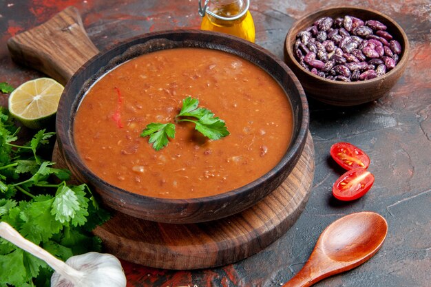 Vista ravvicinata di zuppa di pomodoro e fagioli su un tagliere su una tavola di colori misti