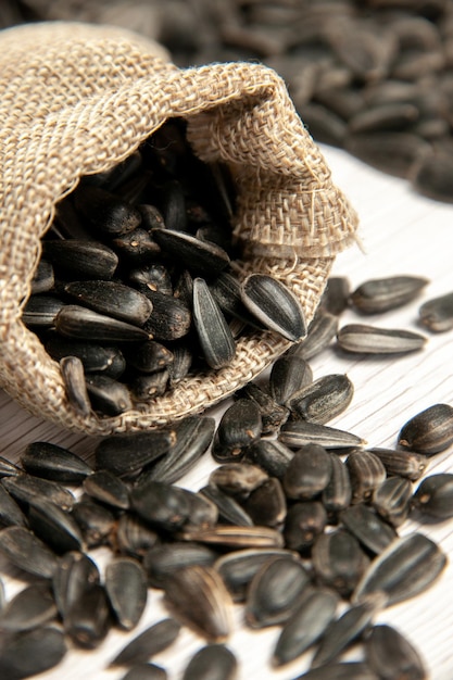 Vista ravvicinata frontale semi di girasole freschi semi neri su luce bianca scrivania foto olio snack molti semi