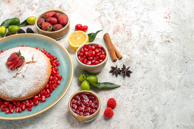 Vista ravvicinata laterale della torta con frutti di bosco, limone, cannella, anice stellato, bacche nelle ciotole