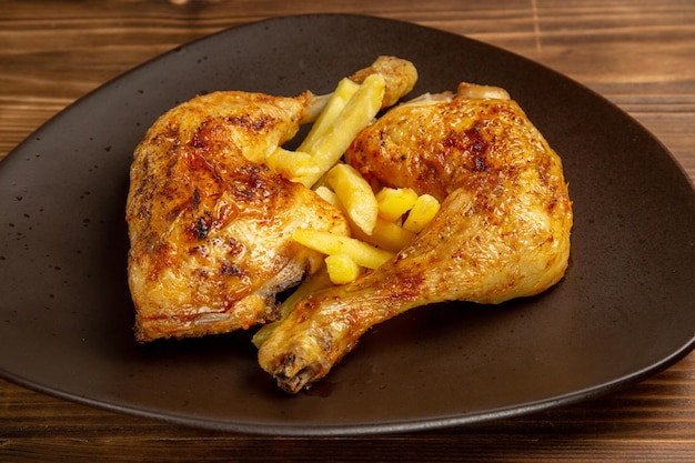 Vista ravvicinata laterale di cosce di pollo piatto di cosce di pollo e patatine fritte al centro del tavolo