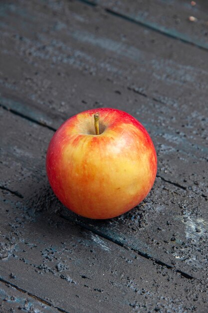 Vista ravvicinata laterale frutta mela giallo-rossastra su un tavolo di legno grigio