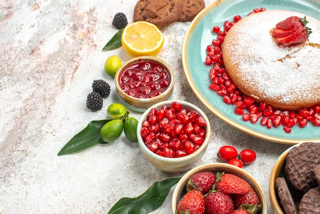 Vista ravvicinata laterale frutti di bosco marmellata di limone melograno la torta con fragole biscotti al cioccolato