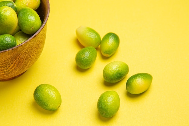 Vista ravvicinata laterale fruttifica i frutti appetitosi accanto alla ciotola sul tavolo giallo