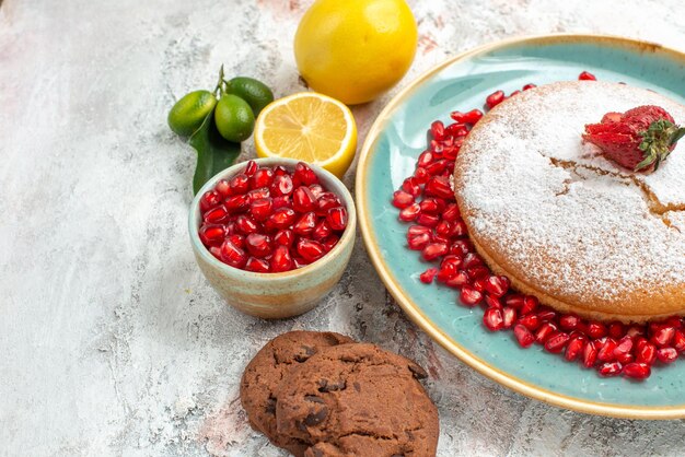 Vista ravvicinata laterale la torta agli agrumi la torta con le fragole i biscotti al melograno