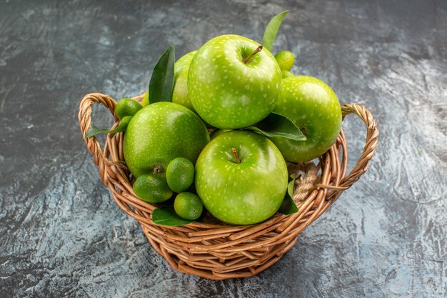 Vista ravvicinata laterale mele mele verdi con foglie di agrumi nel cestino