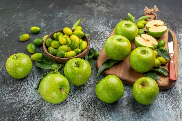 Vista ravvicinata laterale mele mele verdi con foglie sulla ciotola di bordo di agrumi