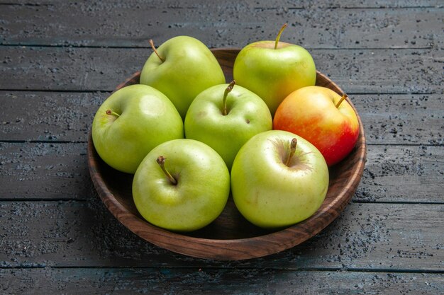 Vista ravvicinata laterale mele verde-giallo-rossastre una ciotola di mele rossastre gialle verdi sul tavolo grigio