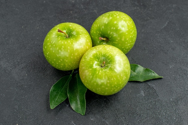Vista ravvicinata laterale mele verdi le appetitose mele verdi con foglie sul tavolo scuro
