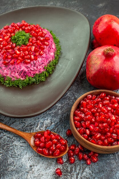 Vista ravvicinata laterale melograni un appetitoso piatto semi di melograno nella ciotola e cucchiaio