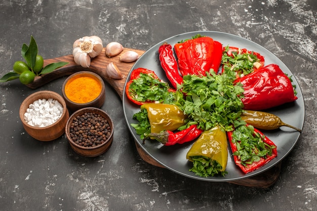 Vista ravvicinata laterale piatto di peperoni piatto di peperoni con erbe aglio sulle spezie tagliere