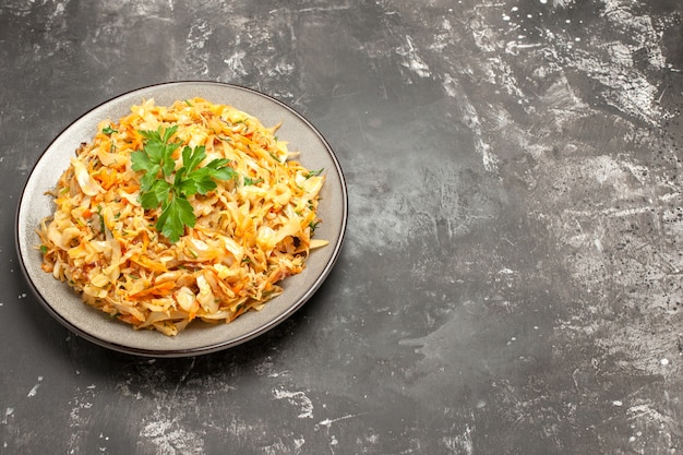 Vista ravvicinata laterale piatto il piatto appetitoso di carote cavolo ed erbe sul piatto bianco