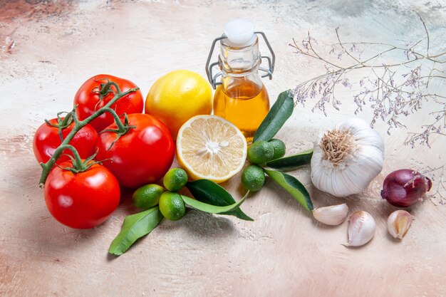 Vista ravvicinata laterale pomodori bottiglia di olio aglio pomodori con pedicelli agrumi