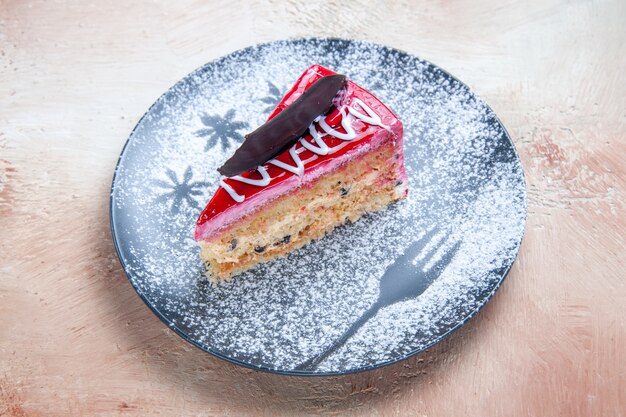 Vista ravvicinata laterale torta una torta appetitosa con creme zucchero a velo sul piatto