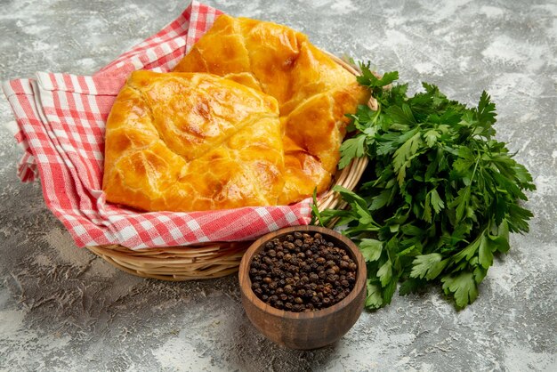 Vista ravvicinata laterale torte e limoni piatto di ciotole di formaggio di erbe al pepe nero accanto al cesto di legno di torte e tovaglia sullo sfondo grigio