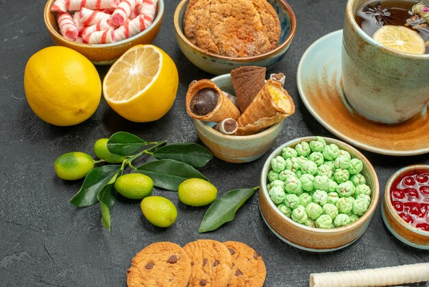 Vista ravvicinata laterale una tazza di tè agli agrumi una tazza di tisane biscotti marmellata dolci