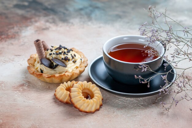 Vista ravvicinata laterale una tazza di tè cupcake una tazza di un appetitoso tè biscotti