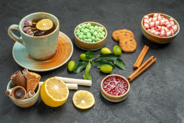 Vista ravvicinata laterale una tazza di tè una tazza di tè biscotti caramelle cialde agrumi cannella