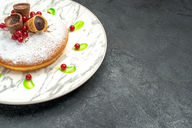 Vista ravvicinata laterale una torta una torta appetitosa con cialde al cioccolato di bacche di zucchero a velo