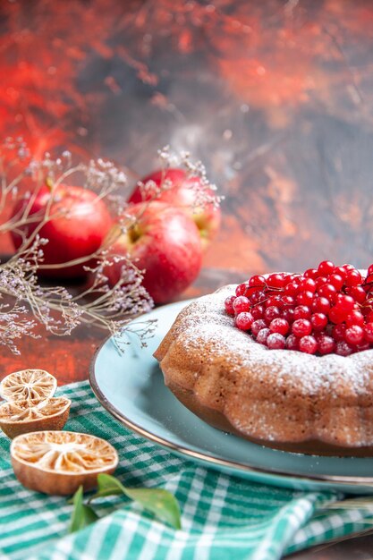 Vista ravvicinata laterale una torta una torta con frutti di bosco sulla tovaglia a scacchi tre rami di mele